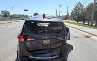 Rear view of a black Chevrolet Equinox with crushed rear hatch and bumper damage after a chain-reaction crash.