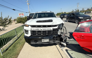 White commercial work truck with front-end damage parked beside a red Honda Civic after a multi-vehicle crash.