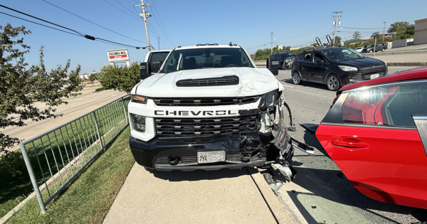 White commercial work truck with front-end damage parked beside a red Honda Civic after a multi-vehicle crash.